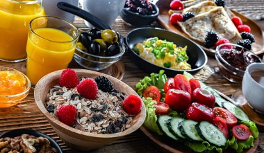 Kahvaltının yanında kahve, portakal suyu, kruvasan, mısır gevreği, çırpılmış yumurta ve krep var..