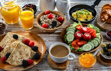 Kahvaltının yanında kahve, portakal suyu, kruvasan, mısır gevreği, çırpılmış yumurta ve krep var..