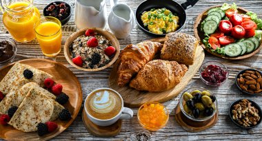 Kahvaltının yanında kahve, portakal suyu, kruvasan, mısır gevreği, çırpılmış yumurta ve krep var..