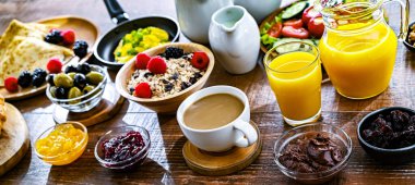 Kahvaltının yanında kahve, portakal suyu, kruvasan, mısır gevreği, çırpılmış yumurta ve krep var..