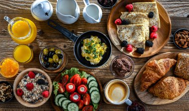 Kahvaltının yanında kahve, portakal suyu, kruvasan, mısır gevreği, çırpılmış yumurta ve krep var..