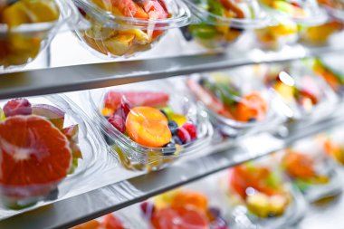 Plastic boxes with pre-packaged fruit salads, put up for sale in a commercial refrigerator