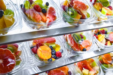Plastic boxes with pre-packaged fruit salads, put up for sale in a commercial refrigerator