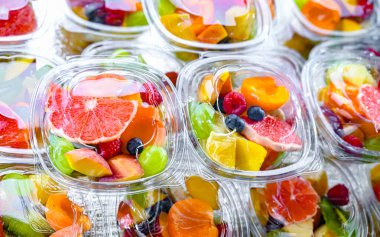 Plastic boxes with pre-packaged fruit salads, put up for sale in a commercial refrigerator