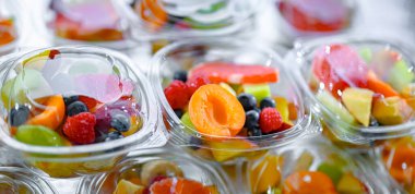 Plastic boxes with pre-packaged fruit salads, put up for sale in a commercial refrigerator
