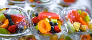 Plastic boxes with pre-packaged fruit salads, put up for sale in a commercial refrigerator clipart