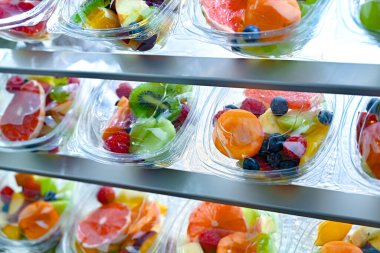 Plastic boxes with pre-packaged fruit salads, put up for sale in a commercial refrigerator