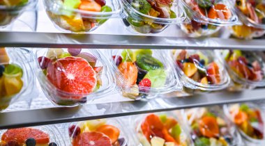 Plastic boxes with pre-packaged fruit salads, put up for sale in a commercial refrigerator