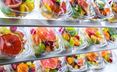 Plastic boxes with pre-packaged fruit salads, put up for sale in a commercial refrigerator clipart