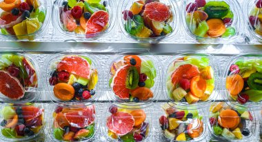 Plastic boxes with pre-packaged fruit salads, put up for sale in a commercial refrigerator