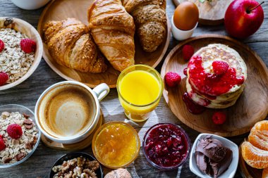 Kahvaltının yanında kahve, portakal suyu, krep, kruvasan, mısır gevreği ve yumurta var..