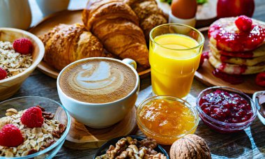 Kahvaltının yanında kahve, portakal suyu, krep, kruvasan, mısır gevreği ve yumurta var..