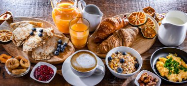 Breakfast served with coffee, orange juice, scrambled eggs, cereals, pancakes and croissants.