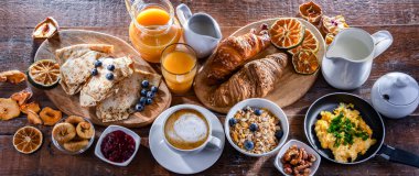 Breakfast served with coffee, orange juice, scrambled eggs, cereals, pancakes and croissants.