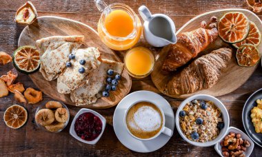Breakfast served with coffee, orange juice, scrambled eggs, cereals, pancakes and croissants.