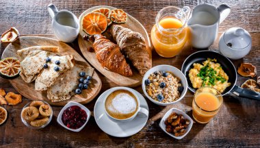 Breakfast served with coffee, orange juice, scrambled eggs, cereals, pancakes and croissants.