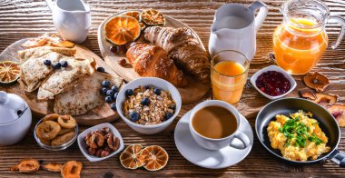 Breakfast served with coffee, orange juice, scrambled eggs, cereals, pancakes and croissants.
