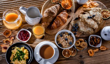 Breakfast served with coffee, orange juice, scrambled eggs, cereals, pancakes and croissants.