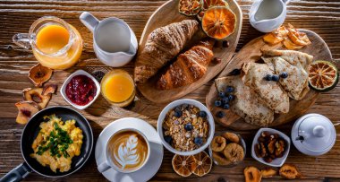 Breakfast served with coffee, orange juice, scrambled eggs, cereals, pancakes and croissants.