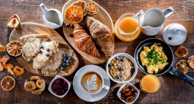 Breakfast served with coffee, orange juice, scrambled eggs, cereals, pancakes and croissants.