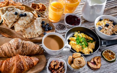 Breakfast served with coffee, orange juice, scrambled eggs, cereals, pancakes and croissants.