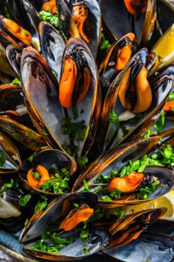 Maydanoz ve limonla servis edilen bir tabak midye kompozisyonu.