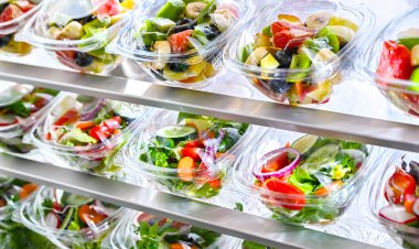 Önceden paketlenmiş meyve ve sebze salatalarıyla dolu plastik kutular ticari bir buzdolabında satılıyor.