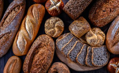 Assorted bakery products including loaves of bread and rolls.