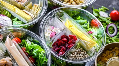 Yuvarlak plastik kutular ve önceden paketlenmiş sebze salataları. Uygun yiyecekler.