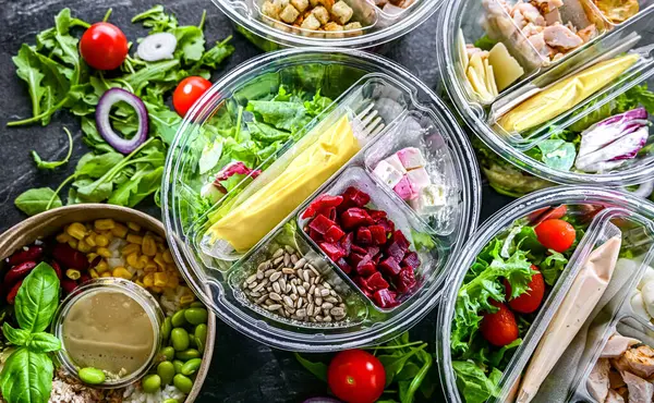 Yuvarlak plastik kutular ve önceden paketlenmiş sebze salataları. Uygun yiyecekler.