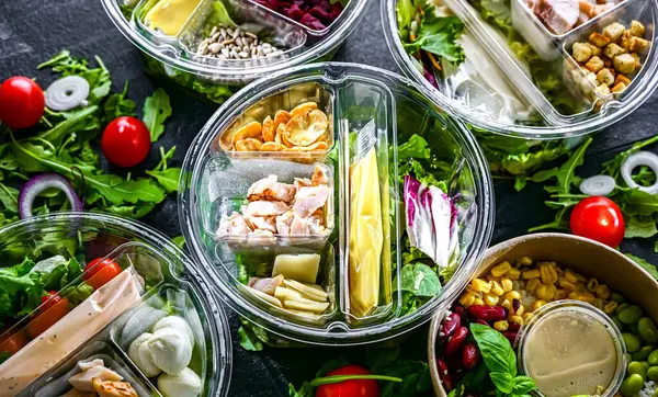 Yuvarlak plastik kutular ve önceden paketlenmiş sebze salataları. Uygun yiyecekler.