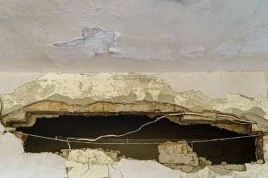 Terk edilmiş bir binanın duvarında büyük bir delik..