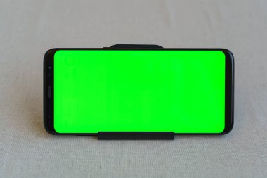 Cep telefonu yeşil ekranlı yatay olarak masada.