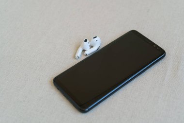Kumaş arka planda izole akıllı telefon ve kablosuz kulaklıklar.