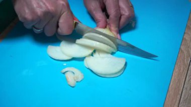 Plastik kesme tahtasında soğan doğrayan kadın..