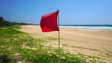 Red square flag on the seashore.