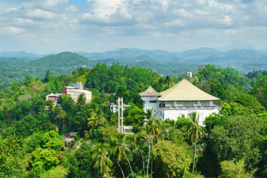 Yeşil tepelerde ve bulutlu gökyüzünde bir ev manzarası.