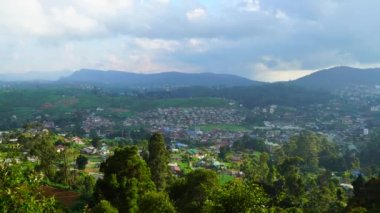 Tepelerin ve bulutlu gökyüzünün ortasındaki köy yerleşimi.