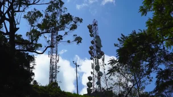 青い空と木々の葉を背景にしたコミュニケーションタワー — ストック動画