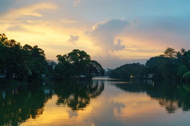 Sri Lanka, Kandy 'deki ağaçların yansımasıyla gölde gün batımı manzarası.