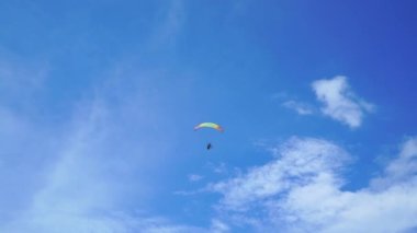 Paraglider mavi gökyüzünde uzaklara uçar.