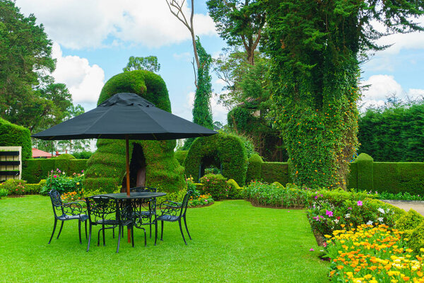 Стол, стулья и зонтик в саду, в зоне отдыха.
