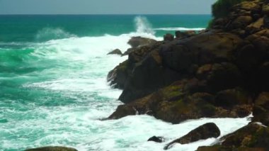 Güçlü okyanus dalgaları kayalık kıyıya vurur ve su sıçrar..