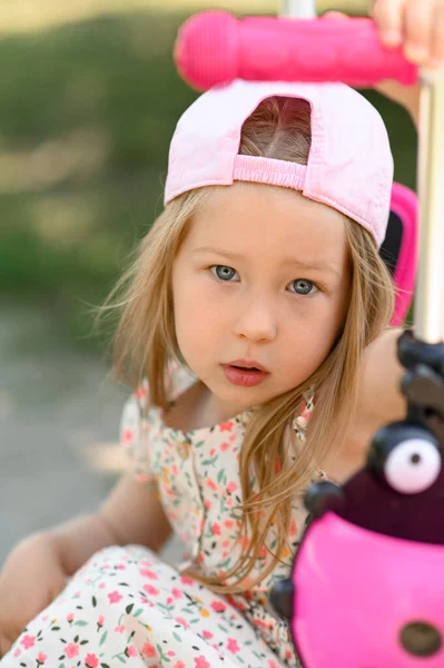 一个戴着粉色帽子的3岁小女孩骑摩托车 夏天的时候靠近点 — 图库照片