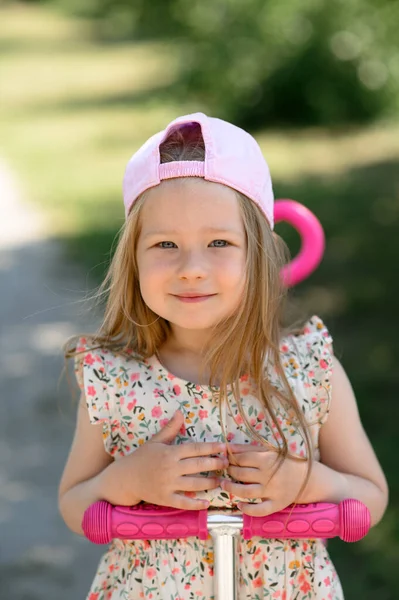 一个戴着粉色帽子的3岁小女孩骑摩托车 夏季时间 — 图库照片