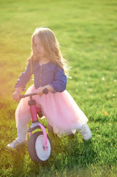 幸せな美しい女の子は速く走り 暖かい夏の日に芝生の上でペダルなしで彼女の最初の自転車に乗ります かわいい赤ちゃん3歳 サイドビュー バランスを保つことを学ぶ — ストック写真