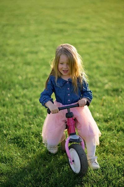 幸せな美しい女の子は速く走り 暖かい夏の日に芝生の上でペダルなしで彼女の最初の自転車に乗ります かわいい赤ちゃん3歳 サイドビュー バランスを保つことを学ぶ — ストック写真