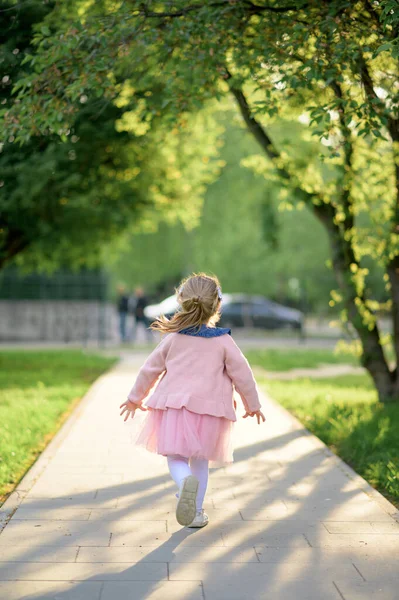 夏のドレス姿で3歳の少女がカメラから逃げ出す 少女は引き返されます 夏時間 ストックフォト