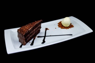 Beyaz tabakta çikolatalı pasta ve siyah arka planda dondurma kompozisyonu.