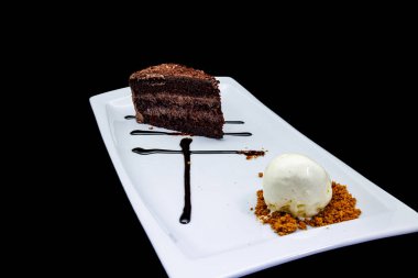 Beyaz tabakta çikolatalı pasta ve siyah arka planda dondurma kompozisyonu.